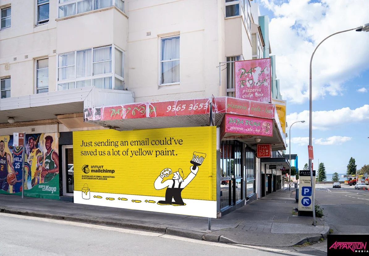 Mailchimp outdoor ad in australia on the side of a building. The ad says "Just sending an email could've saved us a lot of yellow paint."